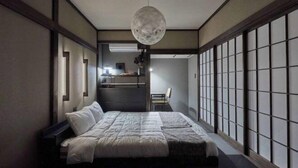 A traditional Japanese-style bedroom with tatami flooring, a low bed, sliding doors, and a hanging moonlight fixture. - VOYAN RESORT Izu MADOKA (Ito)