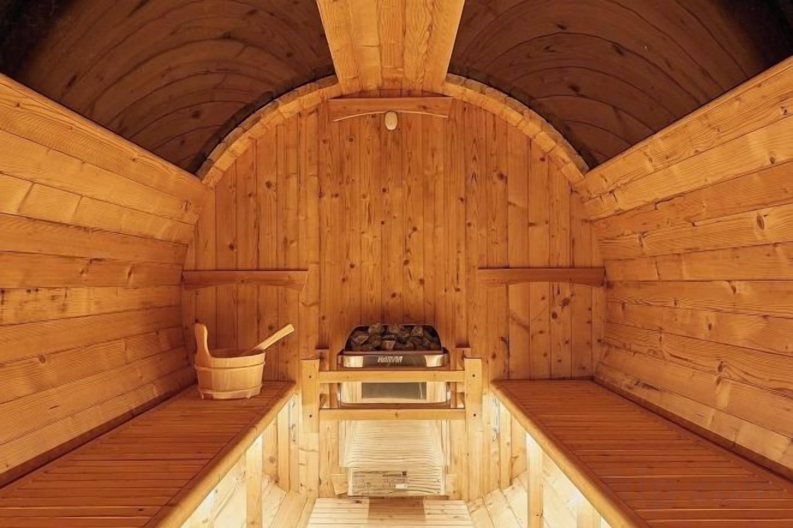 A wooden sauna with benches, a bench, and a heater.