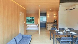 A modern room with a wooden ceiling, a bed, a dining table set for four, and a sofa. - VOYAN RESORT Izu MADOKA (Ito)