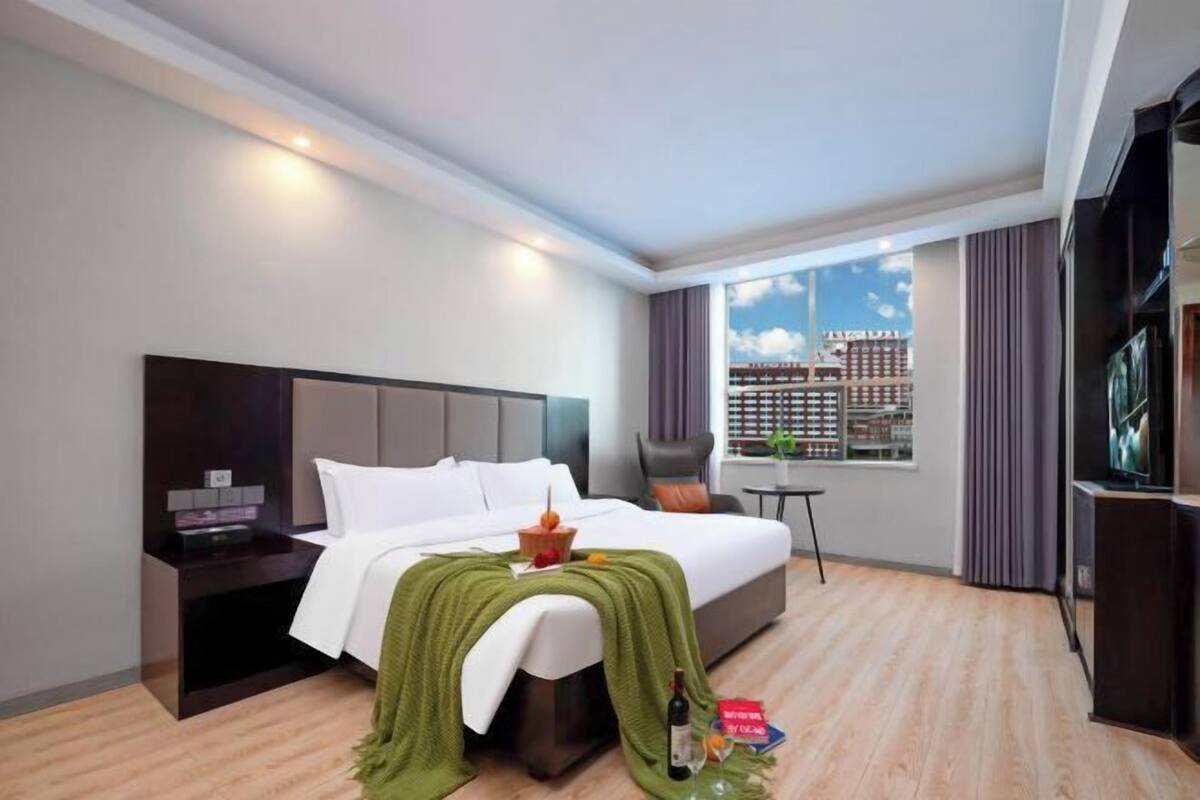 Camera d'albergo moderna con un letto grande, una televisione, un tavolino e una finestra con vista sulla città.