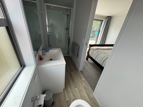 Un baño pequeño con ducha, inodoro y lavamanos.