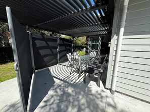 Un patio techado con una mesa y sillas, una puerta corrediza y suelo de hormigón.