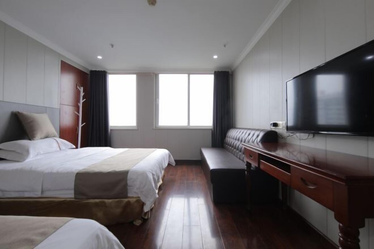 Ein Hotelzimmer mit einem großen Bett, einer Couch, einem Schreibtisch und einem Fernseher.