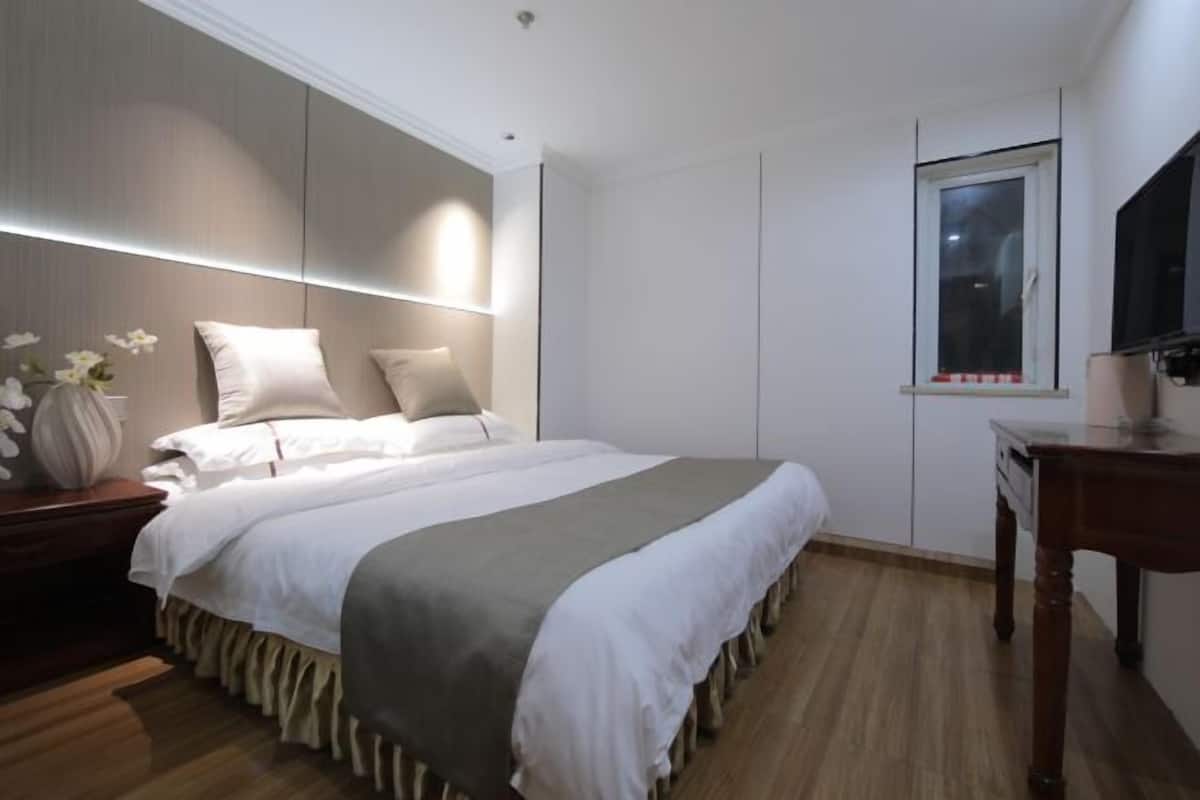 Une chambre à coucher avec un lit, une table de chevet, une lampe et une fenêtre.