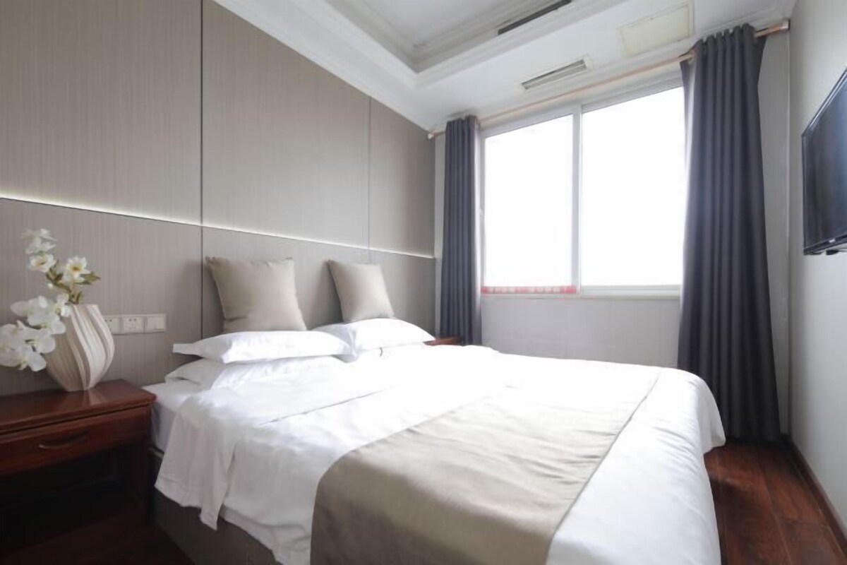 Une chambre d’hôtel avec un lit, une table de chevet et une fenêtre avec des rideaux.