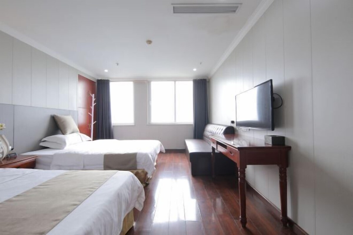 Une chambre d’hôtel avec deux lits, un bureau, un téléviseur à écran plat et une grande fenêtre.