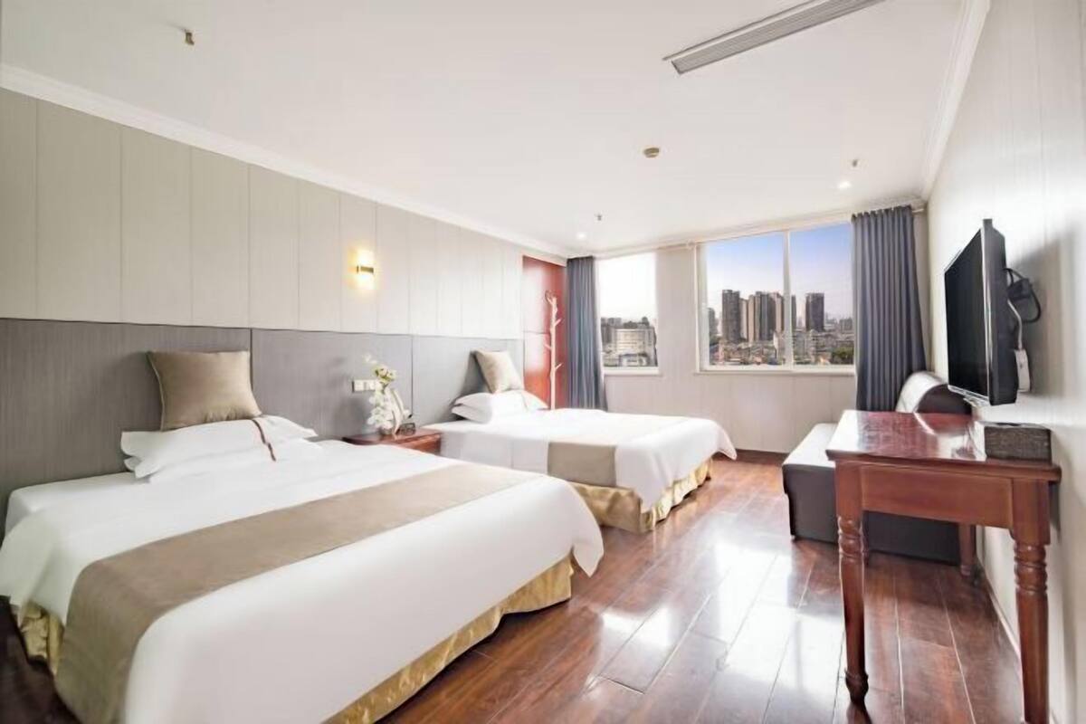 Une chambre d’hôtel avec deux lits, un bureau, une télévision et une vue sur la ville.