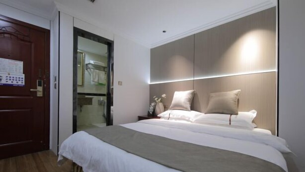 Une chambre d’hôtel moderne avec un grand lit, un plancher en bois, une armoire et une porte ornée d’un calendrier.