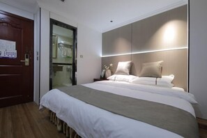 Une chambre d’hôtel moderne avec un grand lit, un plancher en bois, une armoire et une porte ornée d’un calendrier.