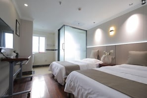 Une chambre d’hôtel avec deux lits, un bureau et une cloison en verre.