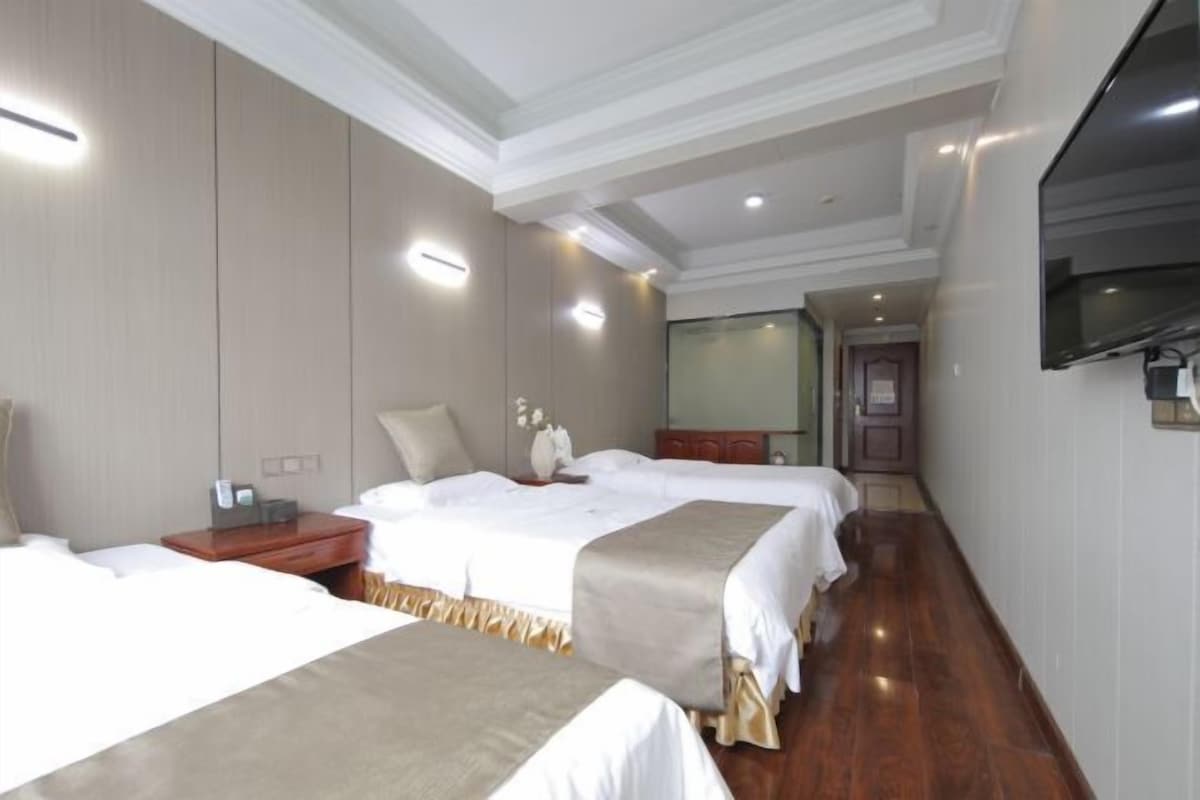 Une chambre d’hôtel avec deux lits, un téléviseur fixé au mur et un plancher en bois.