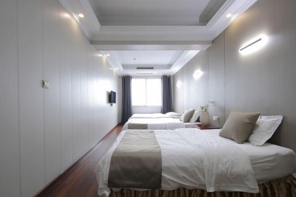 Une chambre d’hôtel avec deux lits, un téléviseur à écran plat, une fenêtre avec des rideaux et un plafond doté d’un éclairage encastré.