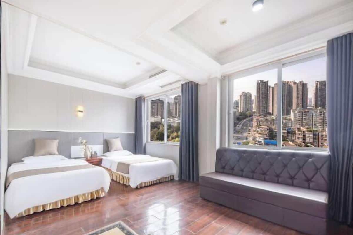 Une chambre d’hôtel avec deux lits, un coin salon et une vue sur la ville.