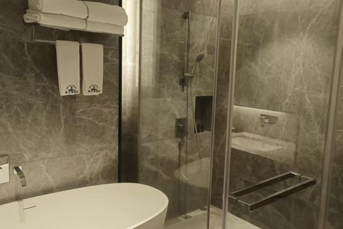 Un bagno moderno con doccia vetrata, lavandino bianco e porta asciugamani.