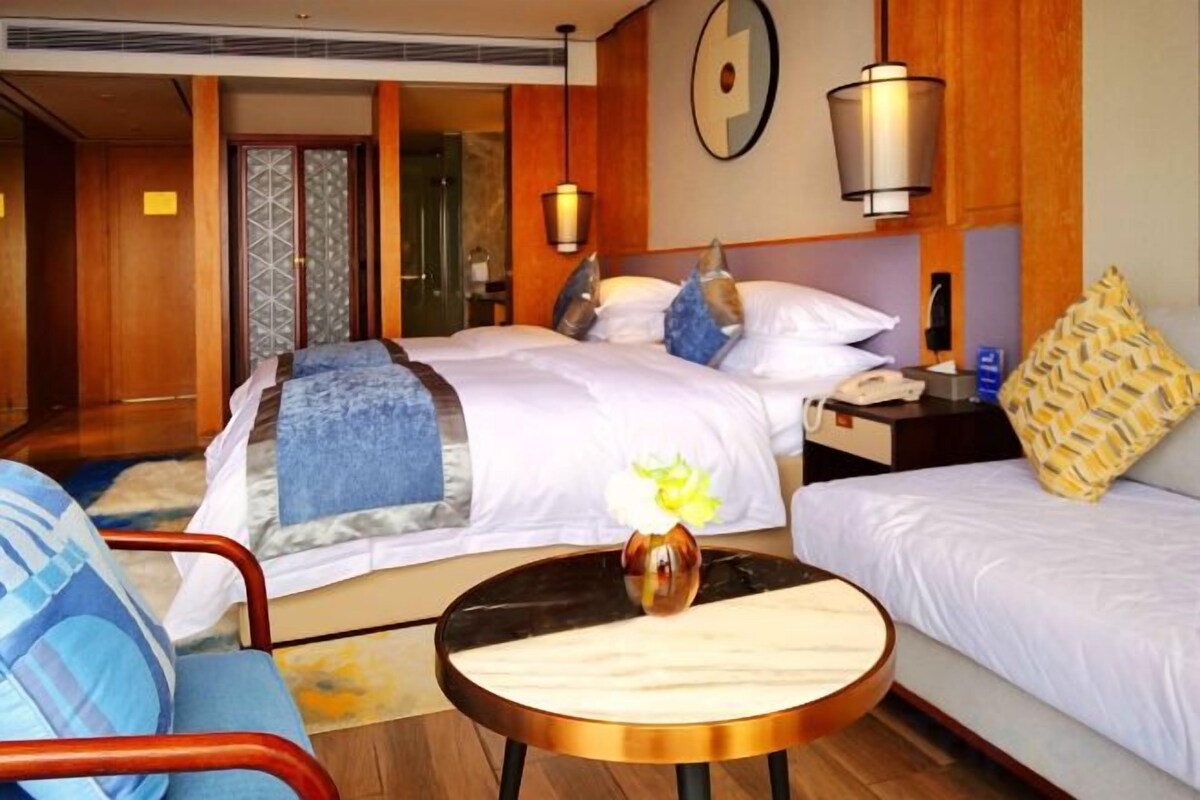 A hotel room with a bed, a bedside table, a lamp, and a chair.