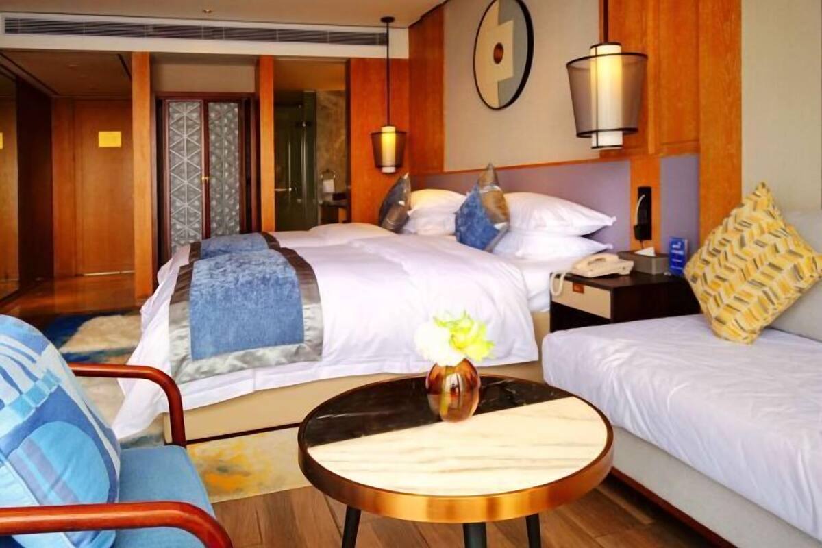 A hotel room with a bed, bedside tables, a chair, and a small table with a vase.