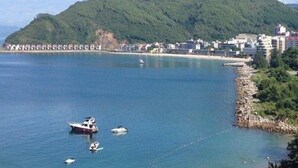 A coastal area with boats, a beach, and a mountain in the background. - Shell BAY Resort (Shenzhen)