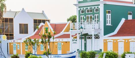 Una calle colorida con edificios tradicionales, un barco azul y una cerca blanca.