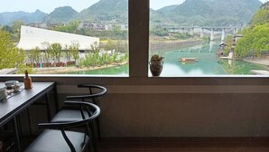 Habitació amb vista a un riu, una taula amb caires i un vas a la finestra.