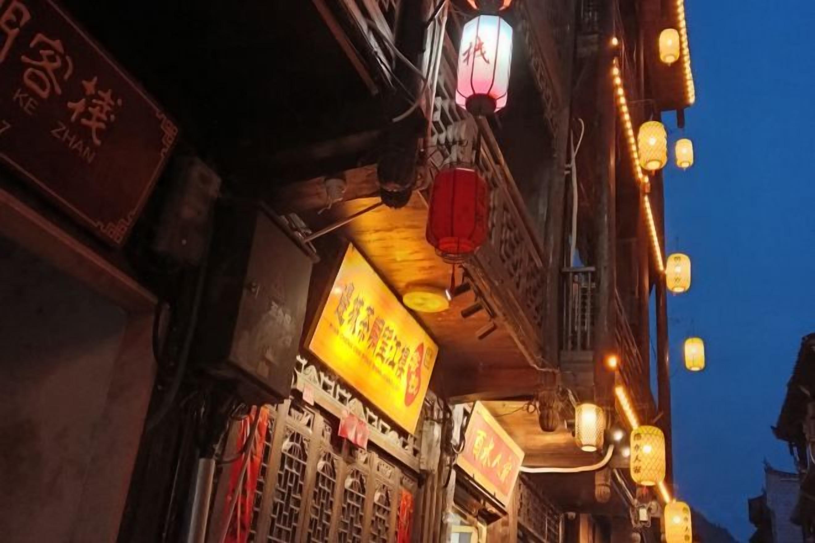 A traditional building facade with illuminated signs and lanterns.