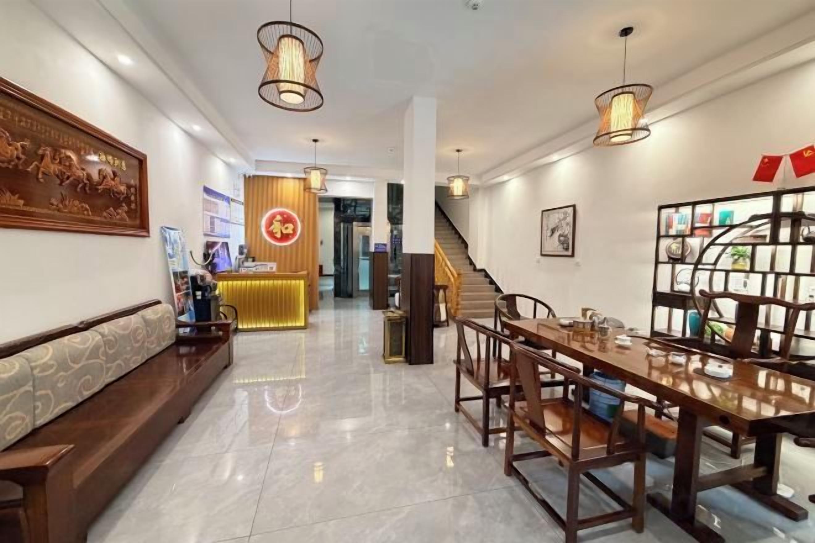 Un vestíbulo de hotel con recepción, zona de estar y escalera.