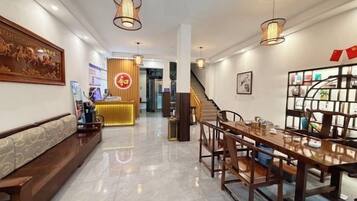Un vestíbulo de hotel con recepción, zona de estar y escalera.