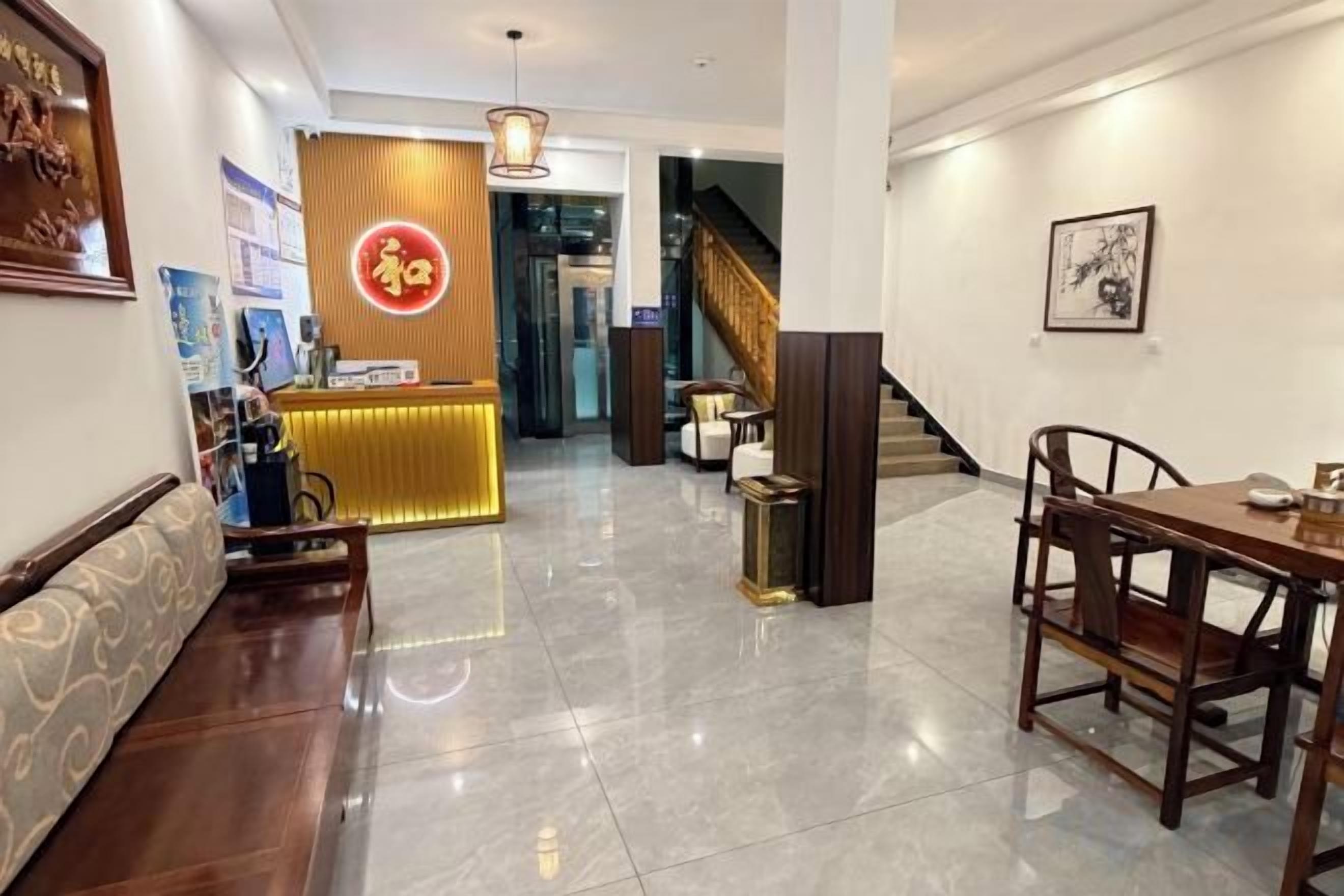Un hall de hotel con mostrador de recepción, zona de estar y una escalera.