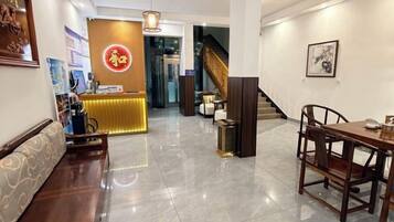 Un hall de hotel con mostrador de recepción, zona de estar y una escalera.