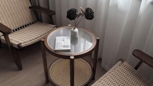 Een ronde glazen tafel met een rieten stoel ernaast.