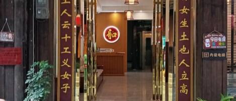 Entrada de hotel con mostrador de recepción y un letrero que indica servicio las 24 horas.