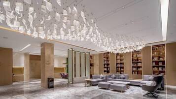 A modern lobby with a high ceiling, a seating area, and bookshelves.