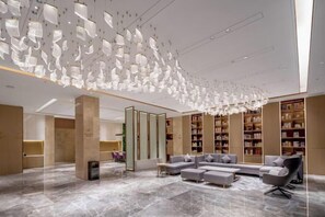 A modern lobby with a high ceiling, a seating area, and bookshelves. - Lavande Hotel Chaozhou Fortune Center Branch (Chaozhou)