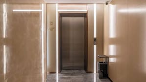 A modern elevator with a control panel, a trash bin, and a marble floor. - Lavande Hotel (Chaozhou Fortune Center) (Chaozhou)