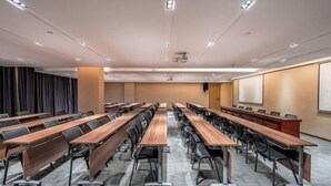 A conference room with long tables, chairs, a projector screen, and a whiteboard. - Lavande Hotel (Chaozhou Fortune Center) (Chaozhou)