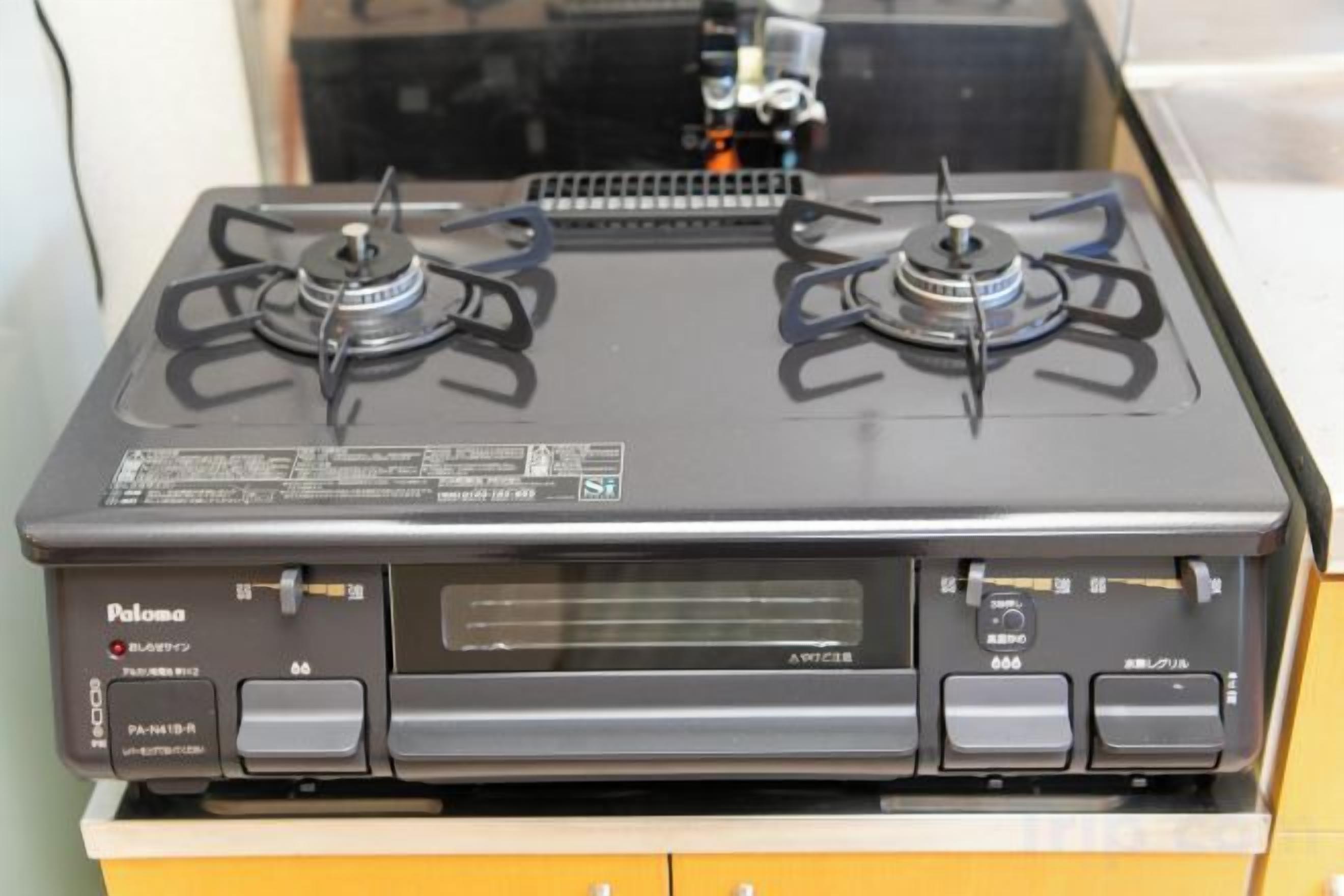 A stove with four burners and a control panel with multiple buttons and a display.