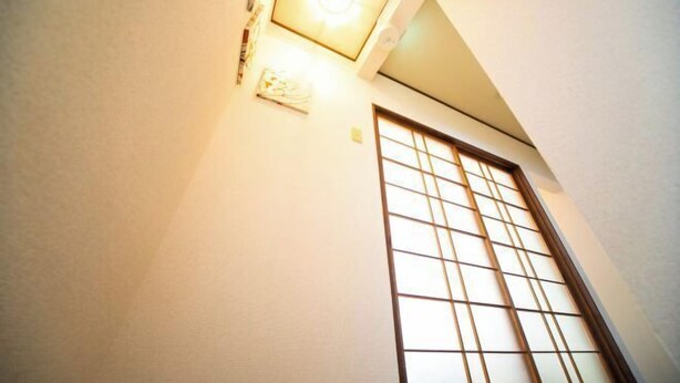 Una habitación con puerta de shoji tradicional y una lámpara en el techo.
