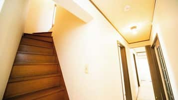 Un pasillo estrecho con una escalera de madera a la izquierda y puertas a la derecha.