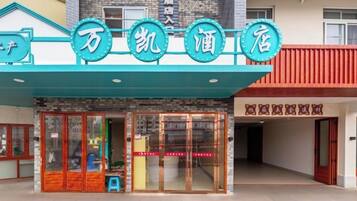 Entrada de hotel com toldo azul e placa com caracteres chineses.