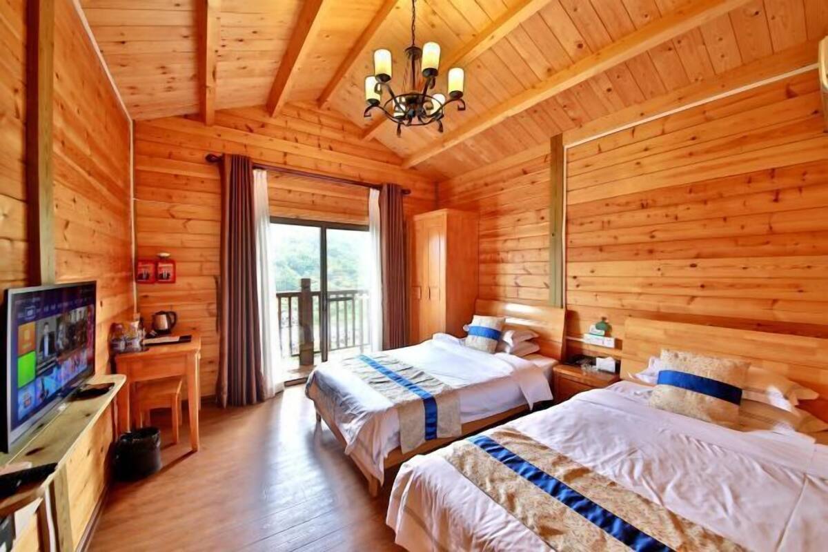 Una cabaña de madera con dos camas, un televisor y un balcón.