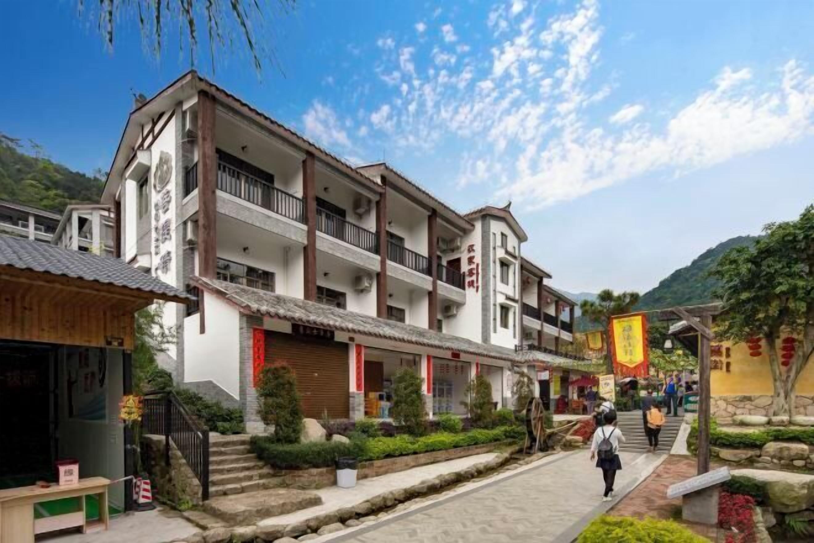 A traditional multi-story building with a balcony, a staircase leading to the entrance, and a clear sky.