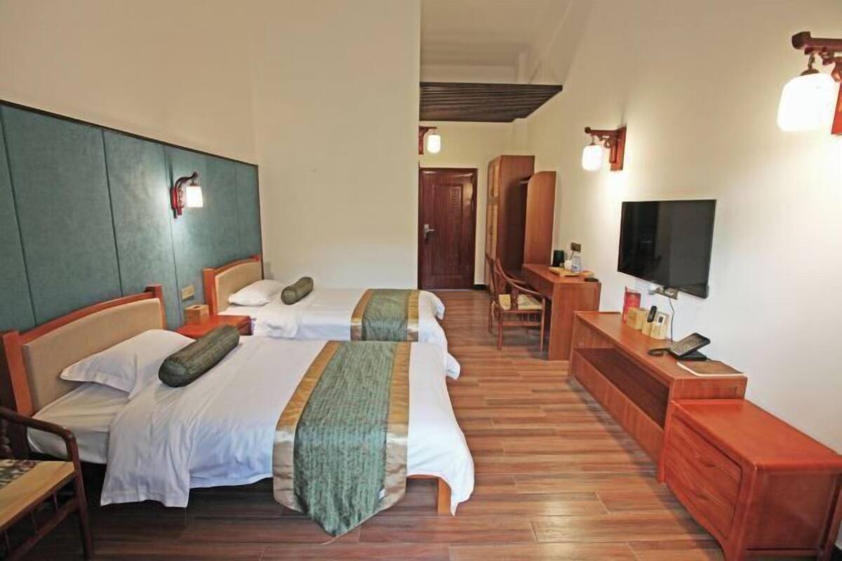 Habitación de hotel con dos camas, un escritorio, un televisor y piso de madera.