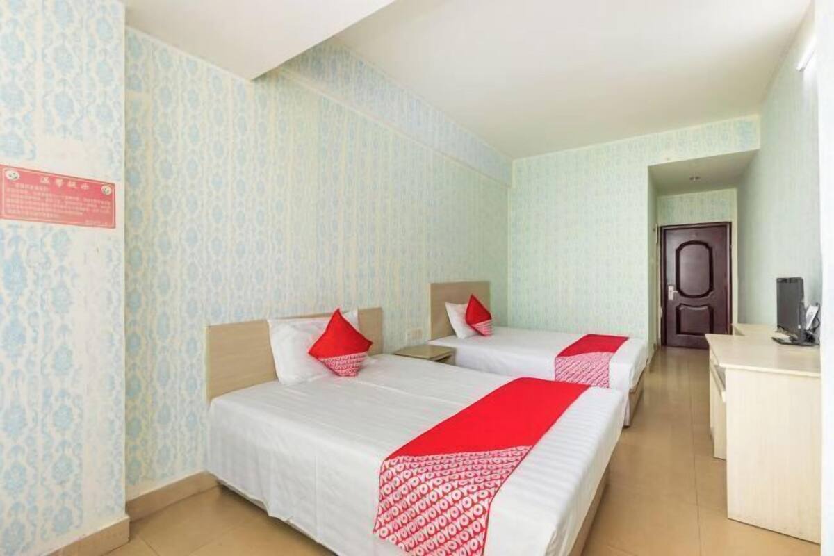 A hotel room with two beds, a desk, and a door.