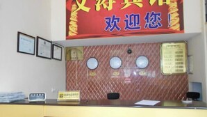 A reception desk with framed certificates, a red sign with Chinese characters, and a bulletin board with papers. - Wentao Hostel (Shanghai)