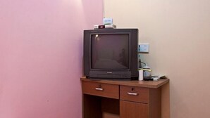 A television on a wooden desk with a pink wall in the background. - Wentao Hostel (Shanghai)