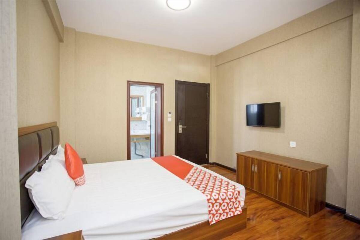 A hotel room with a bed, a television, a wardrobe, and a door leading to another room.