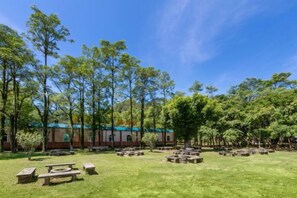 An outdoor area with picnic tables and a building in the background. - Enping Jinjiang Hotspring Hotel (Enping)
