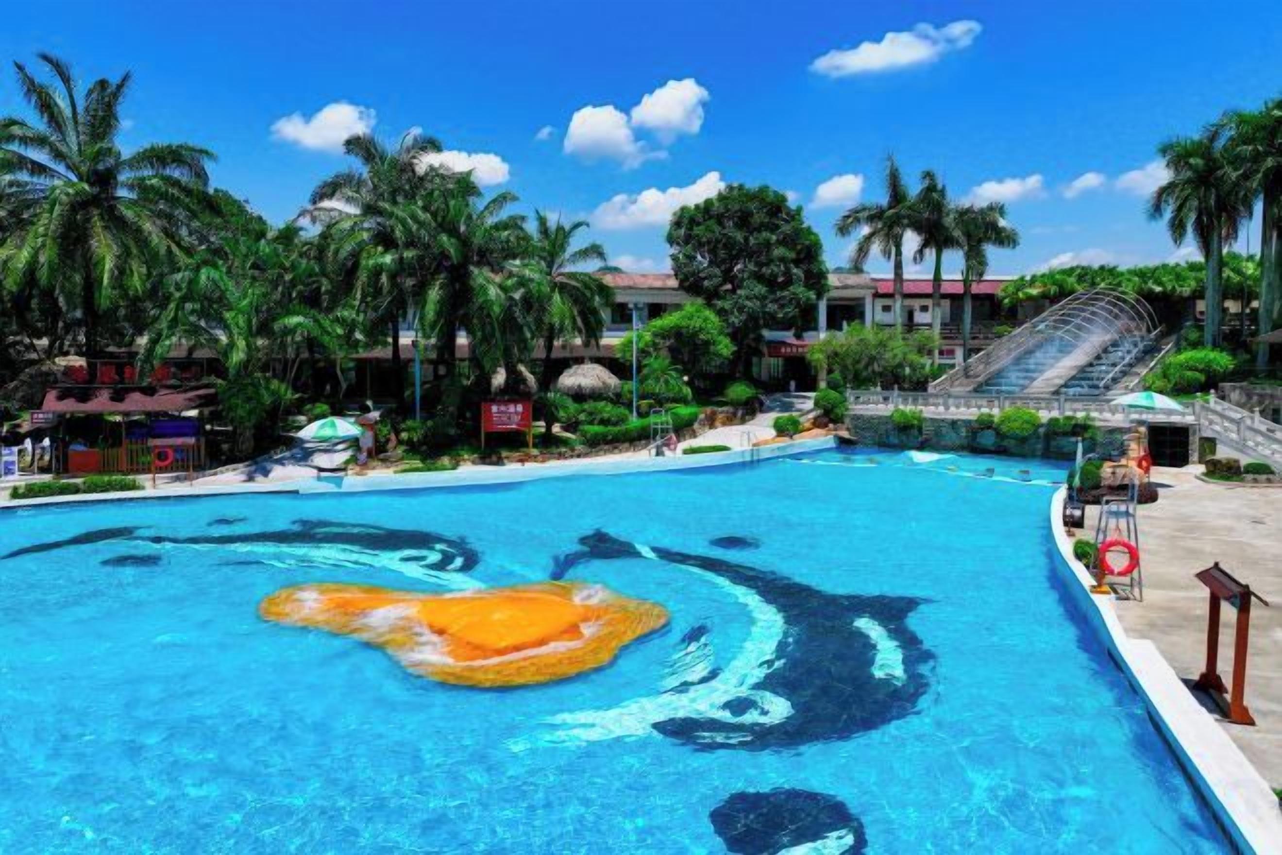 Una piscina con un flotador con forma de delfín, rodeada de palmeras y un edificio de techo rojo.