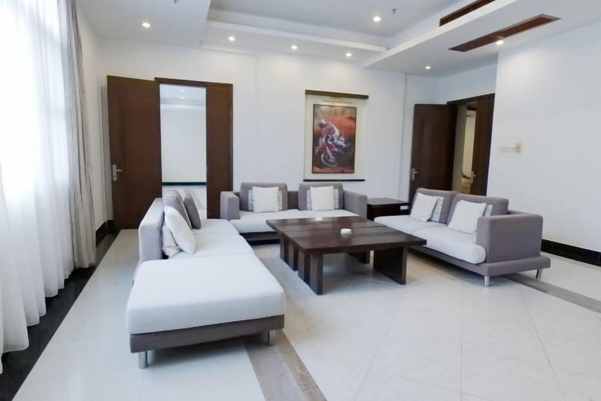 A modern living room with a sectional sofa, a coffee table, and a painting on the wall.