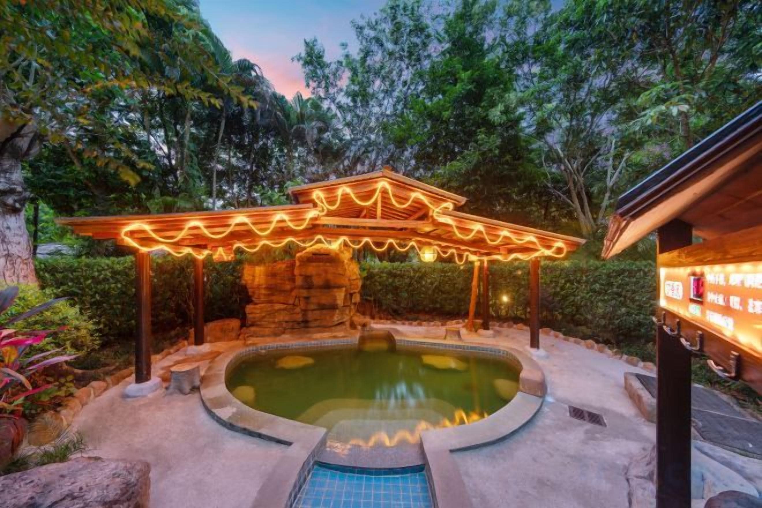 A hot spring area with a stone structure and a wooden pergola.