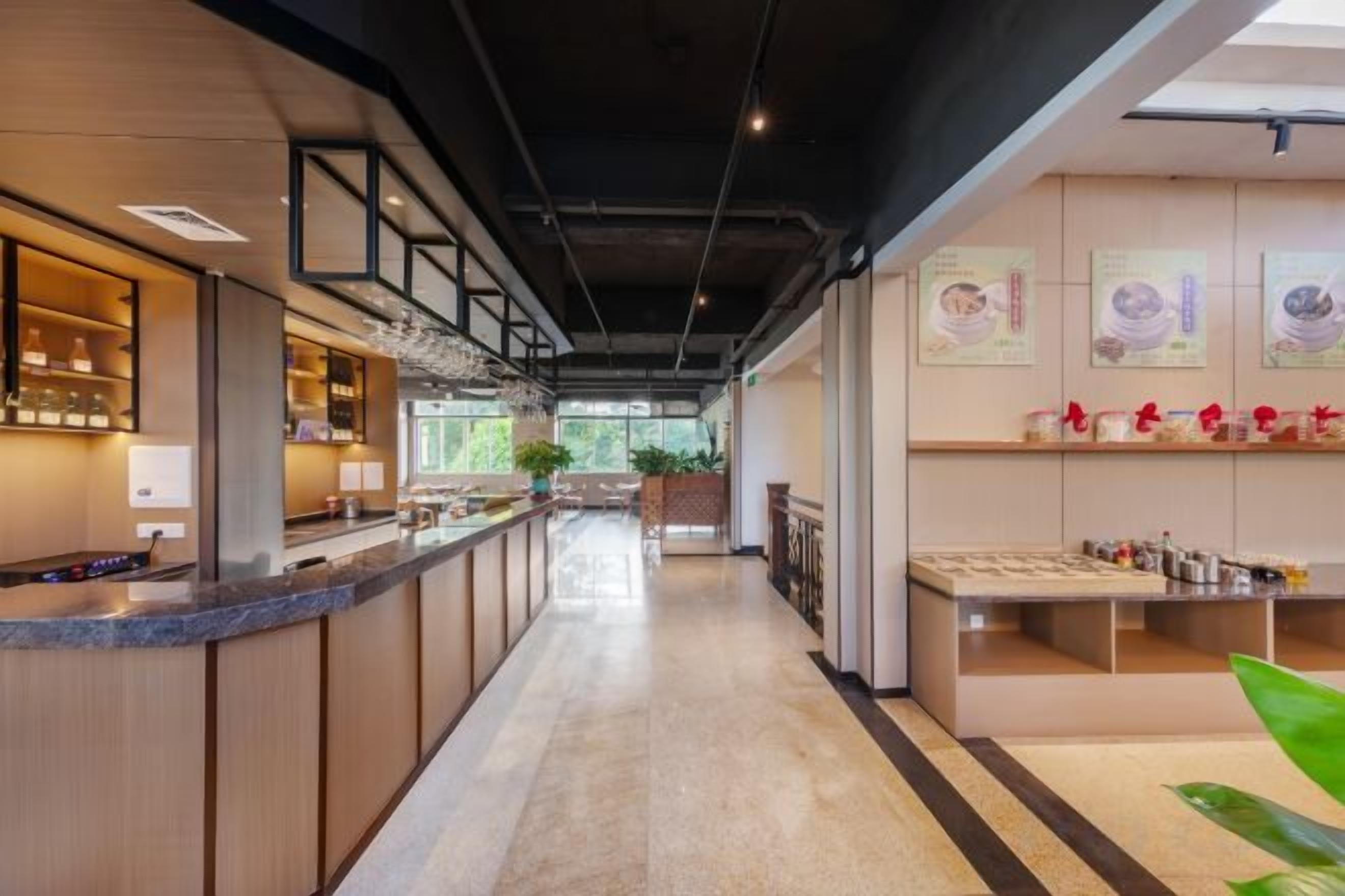 A modern bar area with a long counter, shelves with bottles, and a view of the outdoors.